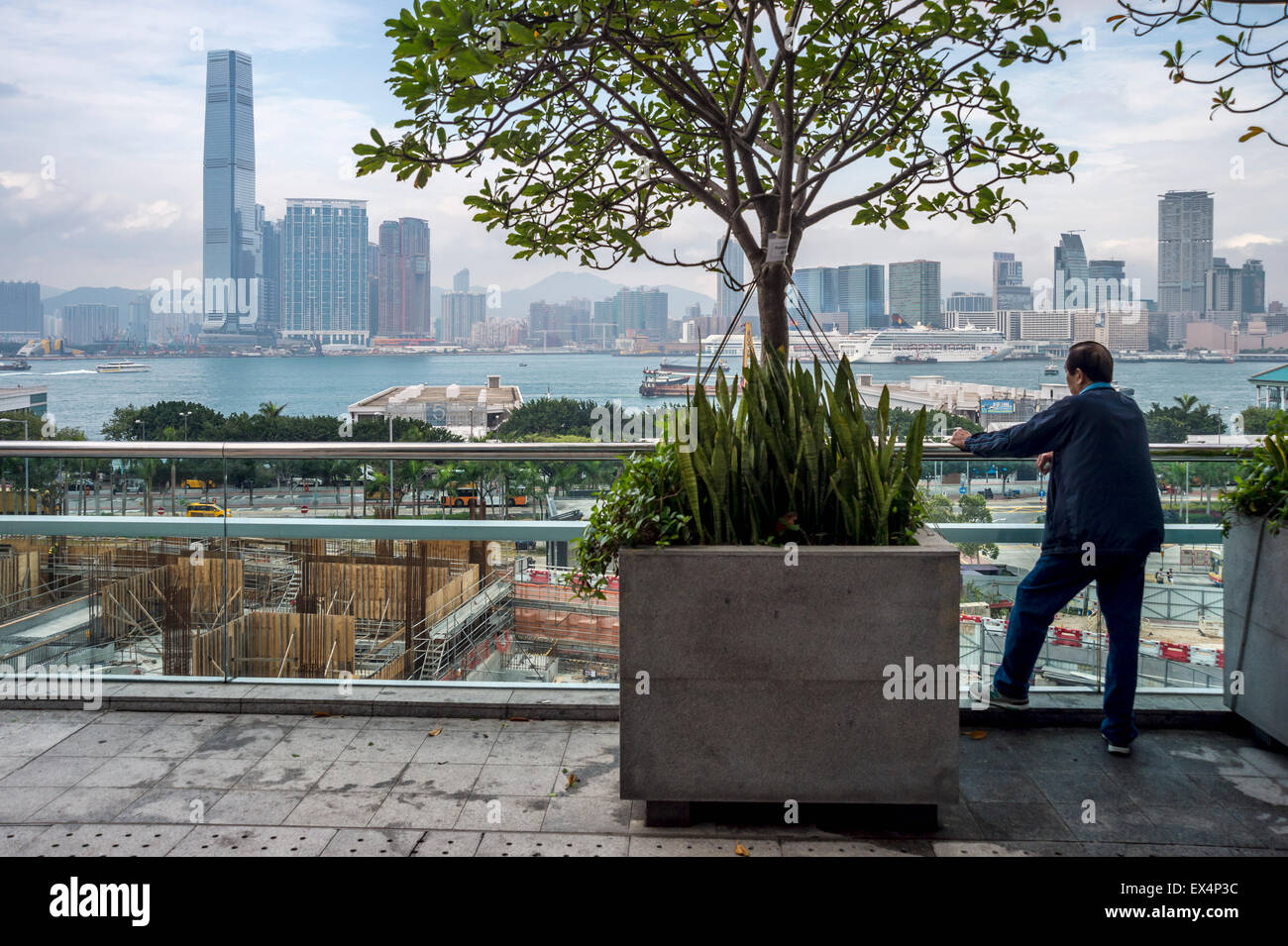 Chinese man looking at Hong Kong Skyline from IFC terrace Stock Photo