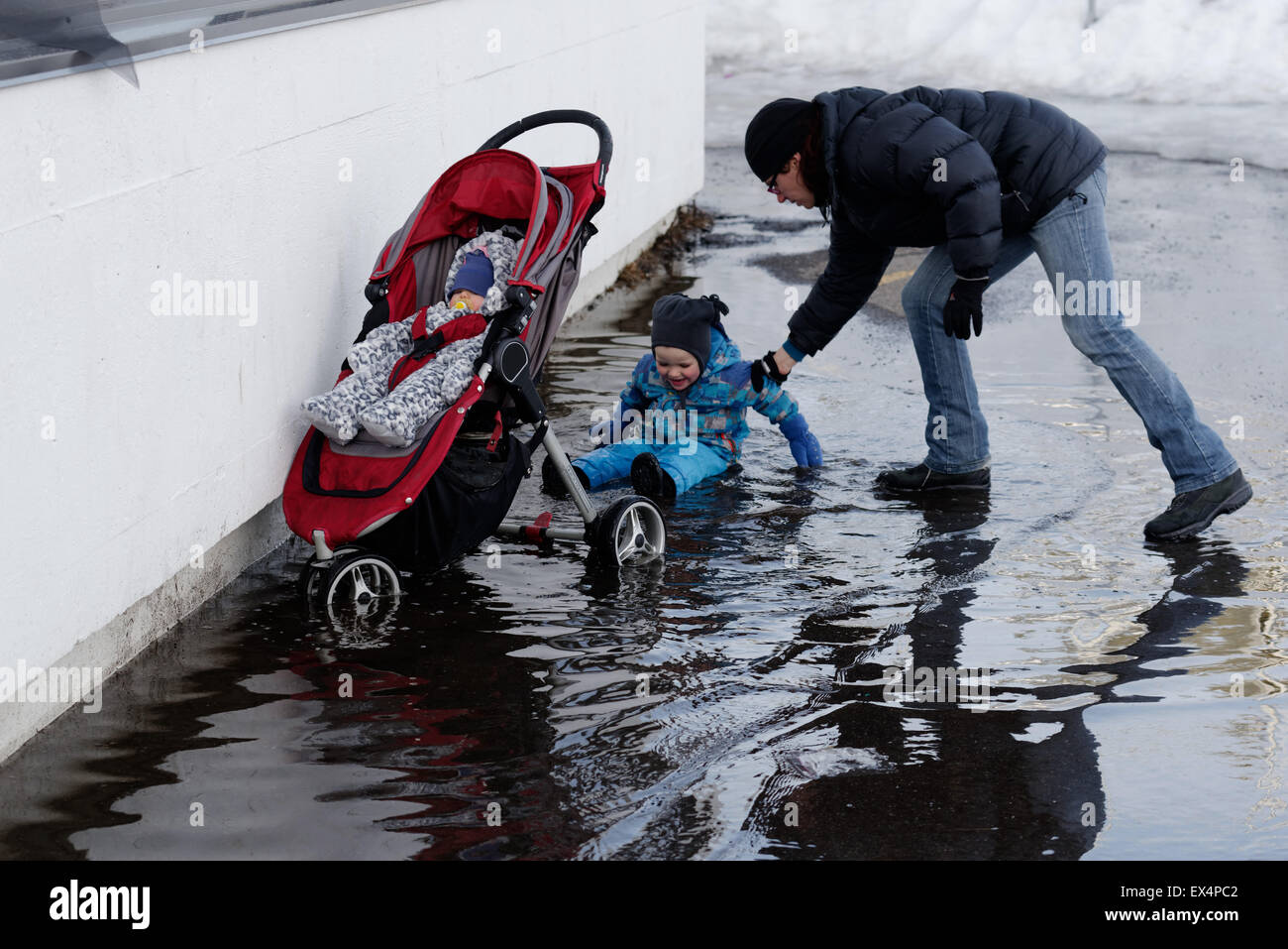 Mum rescuing a little boy who has fallen over in a deep puddle Stock Photo