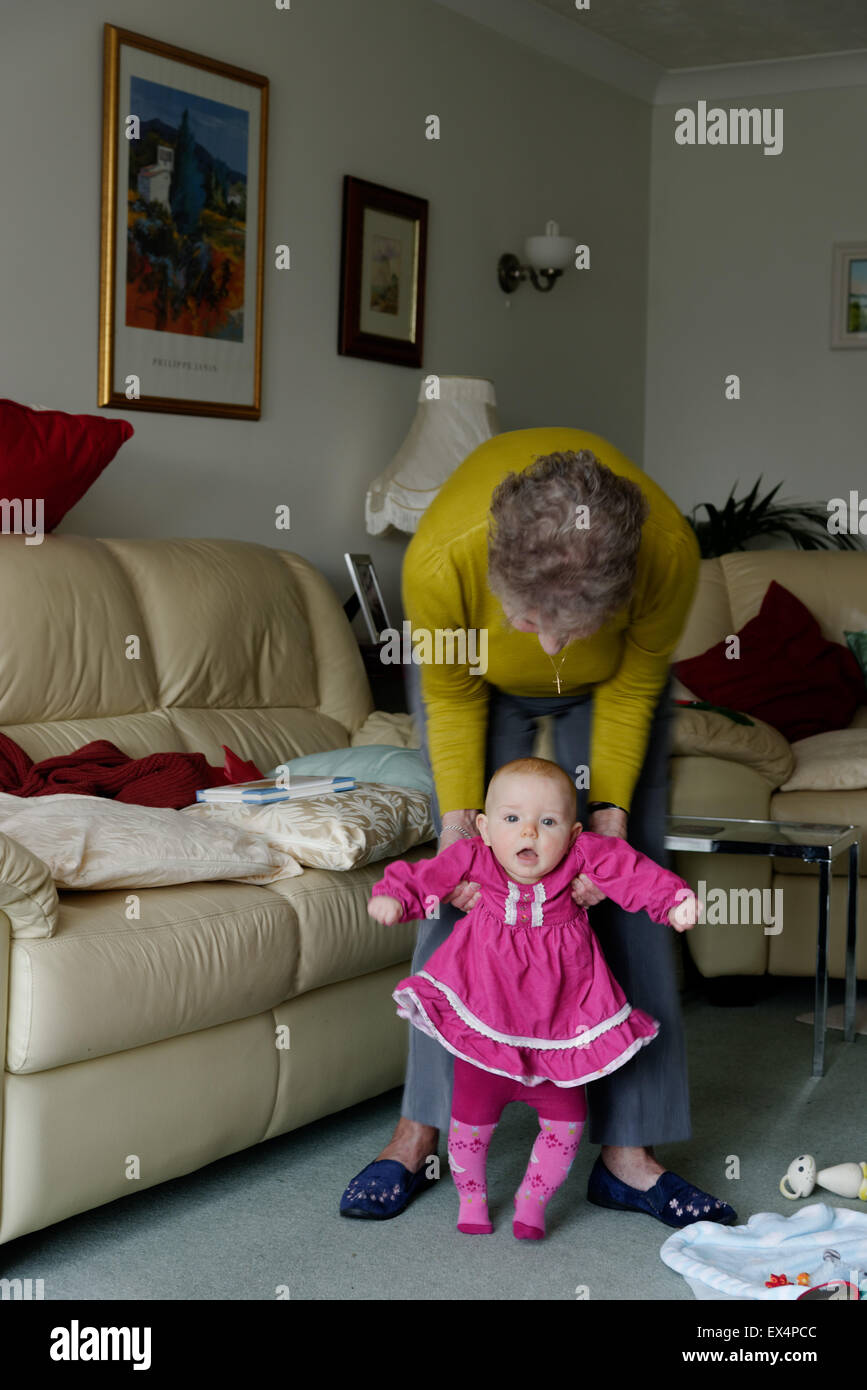 A grandmother teaching her 8 month old grand-daughter to walk Stock Photo