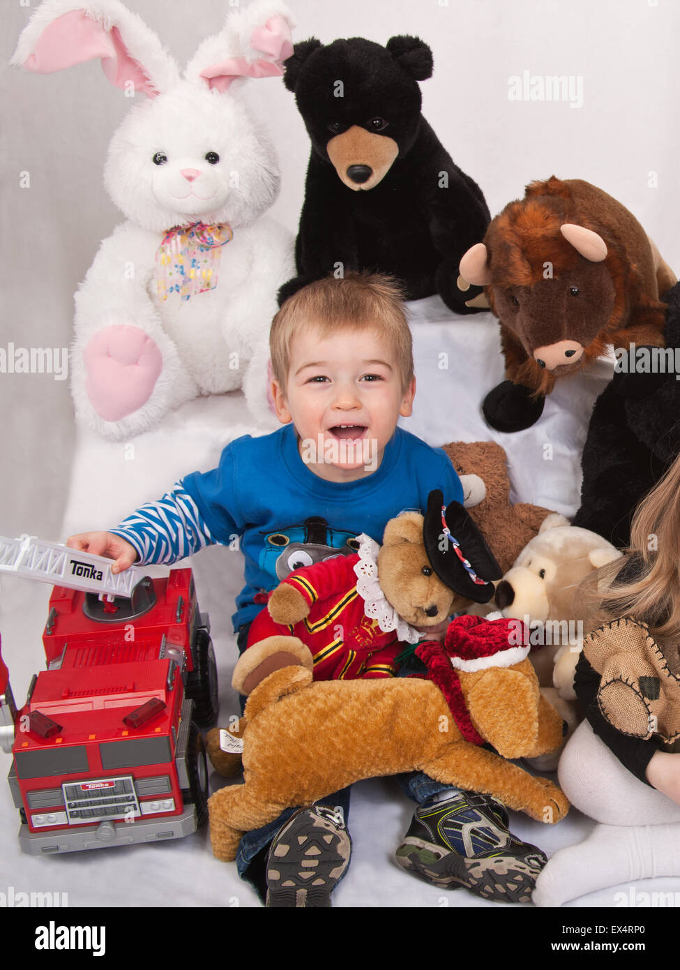 Two year old boy among his collection of stuffed animals and toy fire