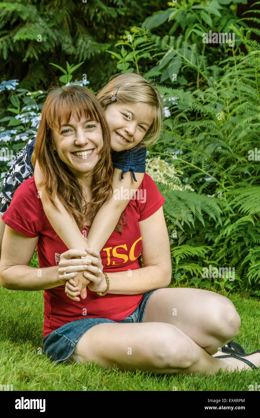 Seven-year old girl hugging her mother outside in a backyard in Issaquah, Washington Stock Photo