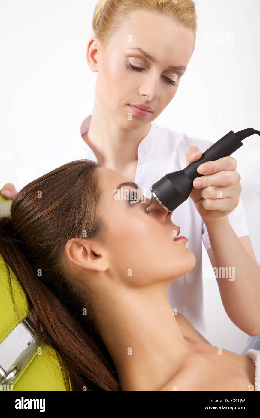 Young brunette woman receiving laser therapy. Spa studio shot Stock Photo
