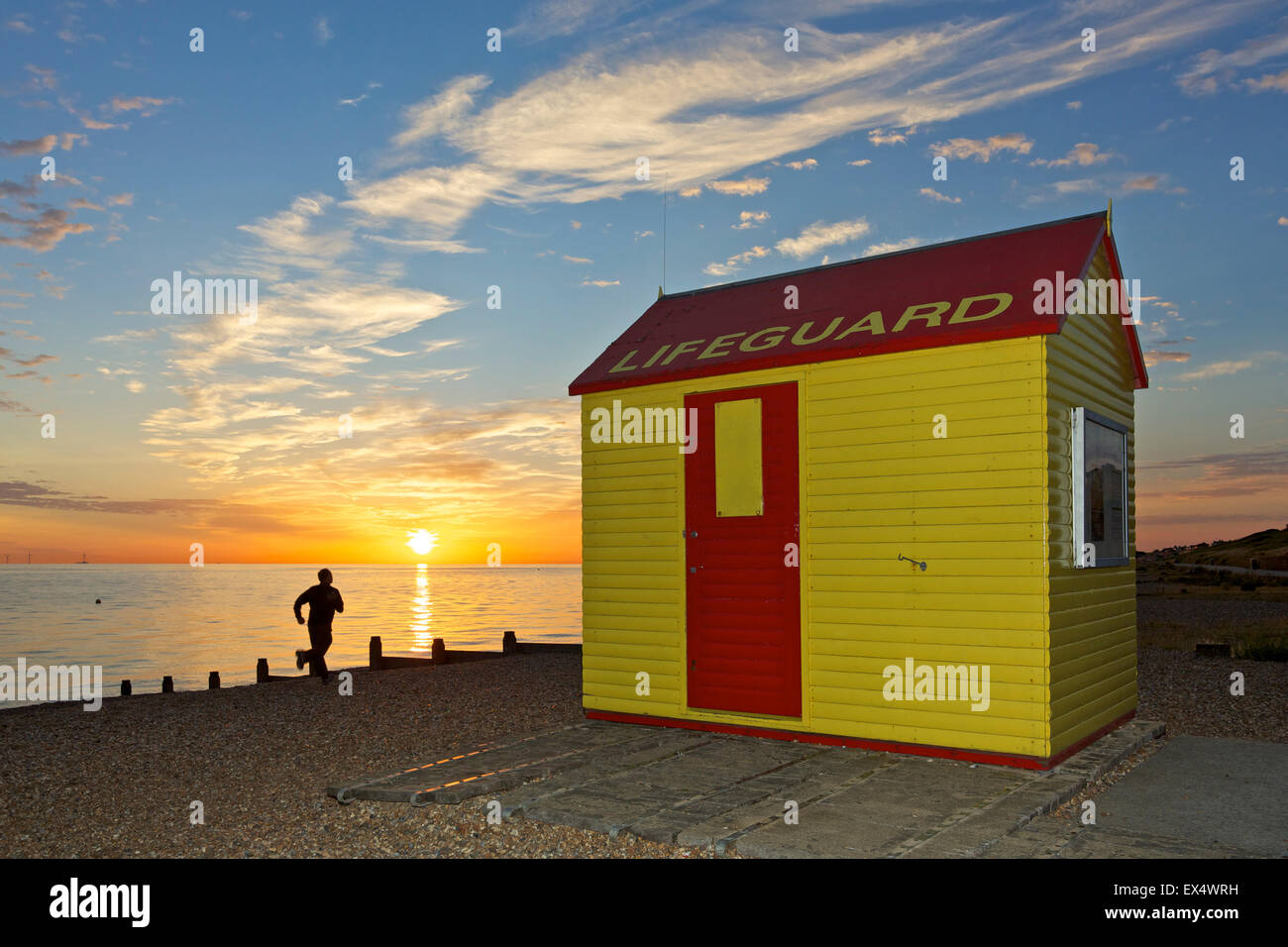Tankerton, Kent, UK. 7th July 2015: UK Weather. Sunrise and a man runs along Tankerton beach near Whitstable in Kent at high tide. Temperatures are forecast to stay in the early 20's for the next few days with some showers Credit:  Alan Payton/Alamy Live News Stock Photo