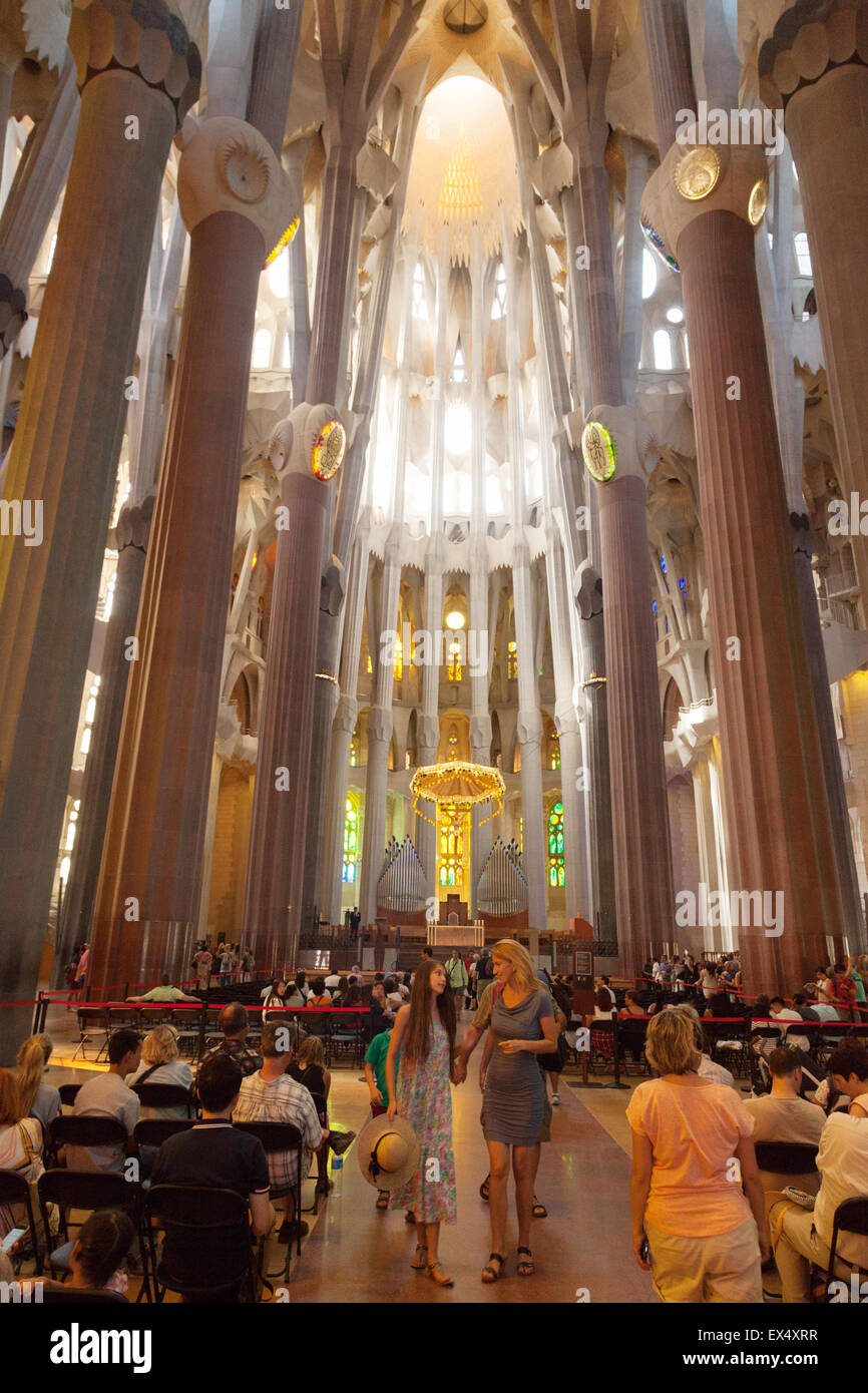 Tourists and local people in the interior, Sagrada Familia cathedral, designed by Antoni Gaudi, Barcelona Spain Europe Stock Photo