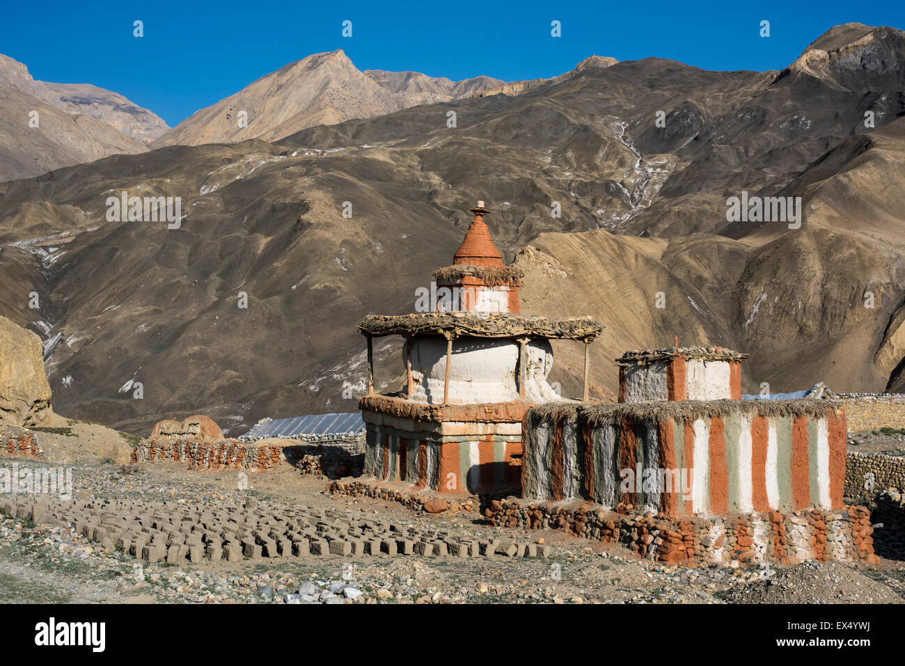 Buddhist stupas in front of mountain landscape, prayer or reliquary shrine, dried mud or adobe bricks on the ground, Tangge Stock Photo