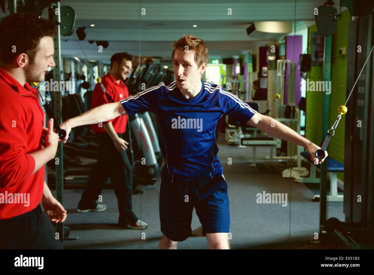 Personal Trainer Instructing Man at Gym Stock Photo