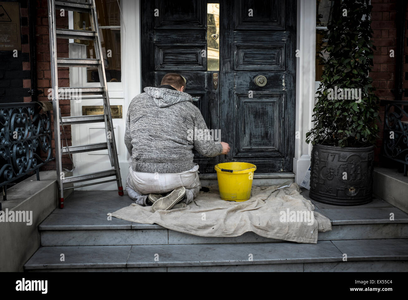 A male decorator preparing the door before painting, London, UK Stock Photo