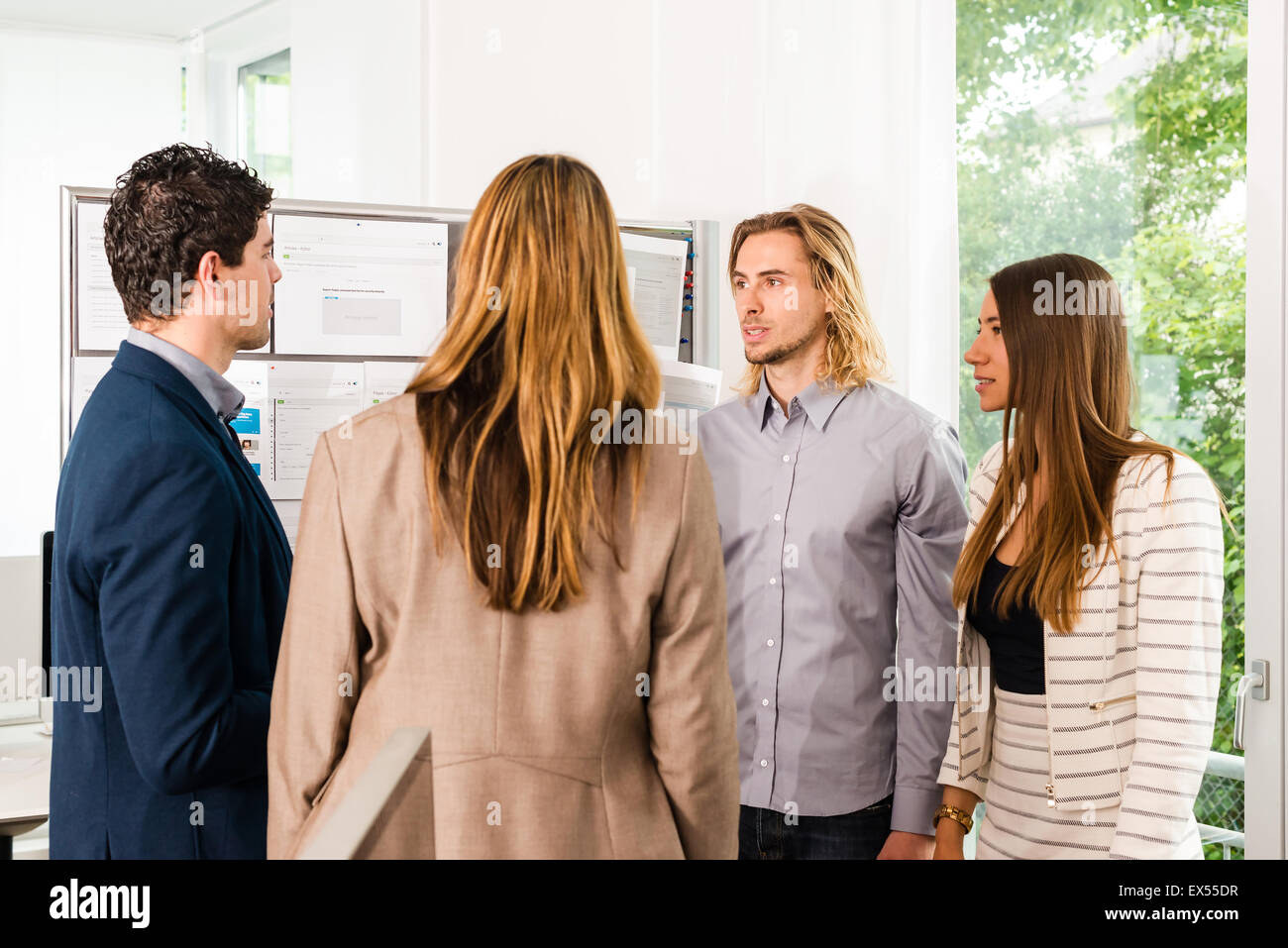 Businesspeople looking at bulletin board in office Stock Photo