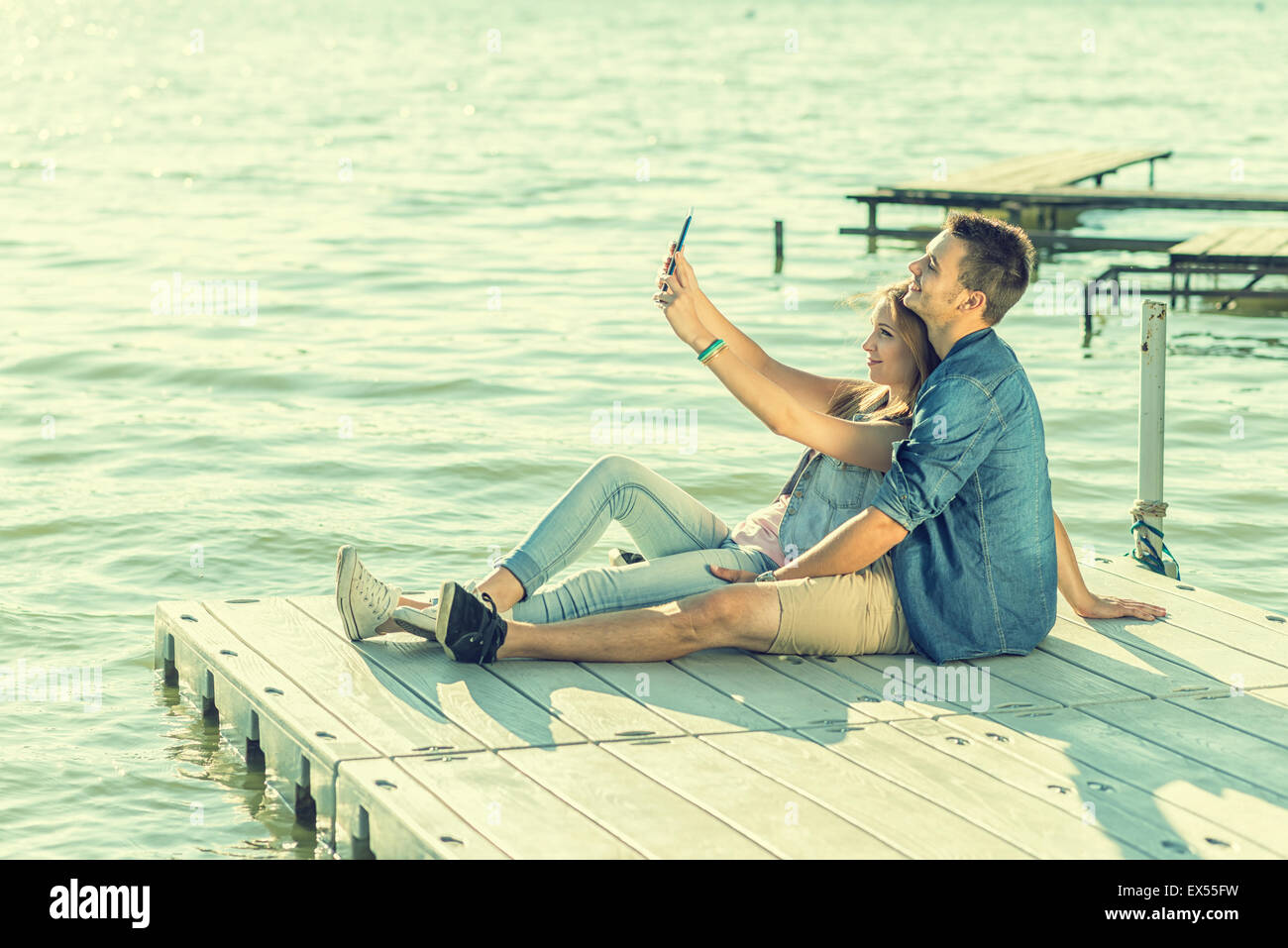 Couple in love sitting on the pier, selfie Stock Photo