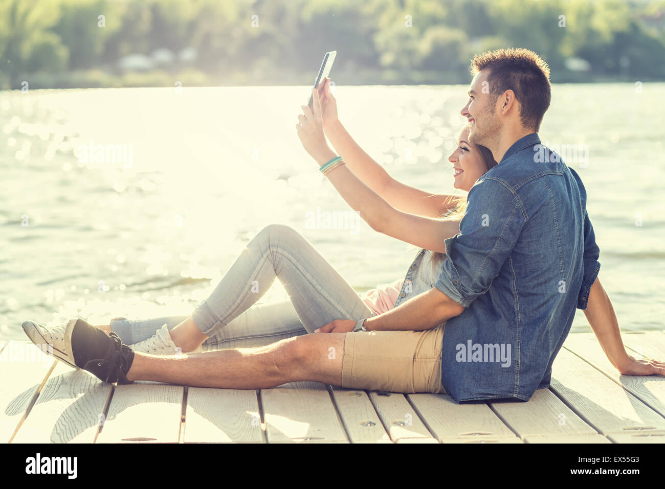 Couple in love sitting on the pier, selfie Stock Photo