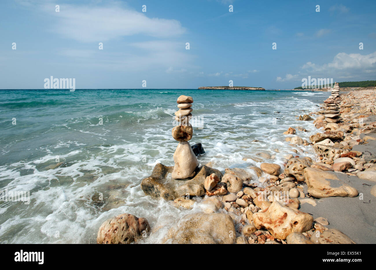 A pile of beach stones made into a sculpture tower on the shoreline of Sant Tomas beach on the island of Menorca Spain Stock Photo