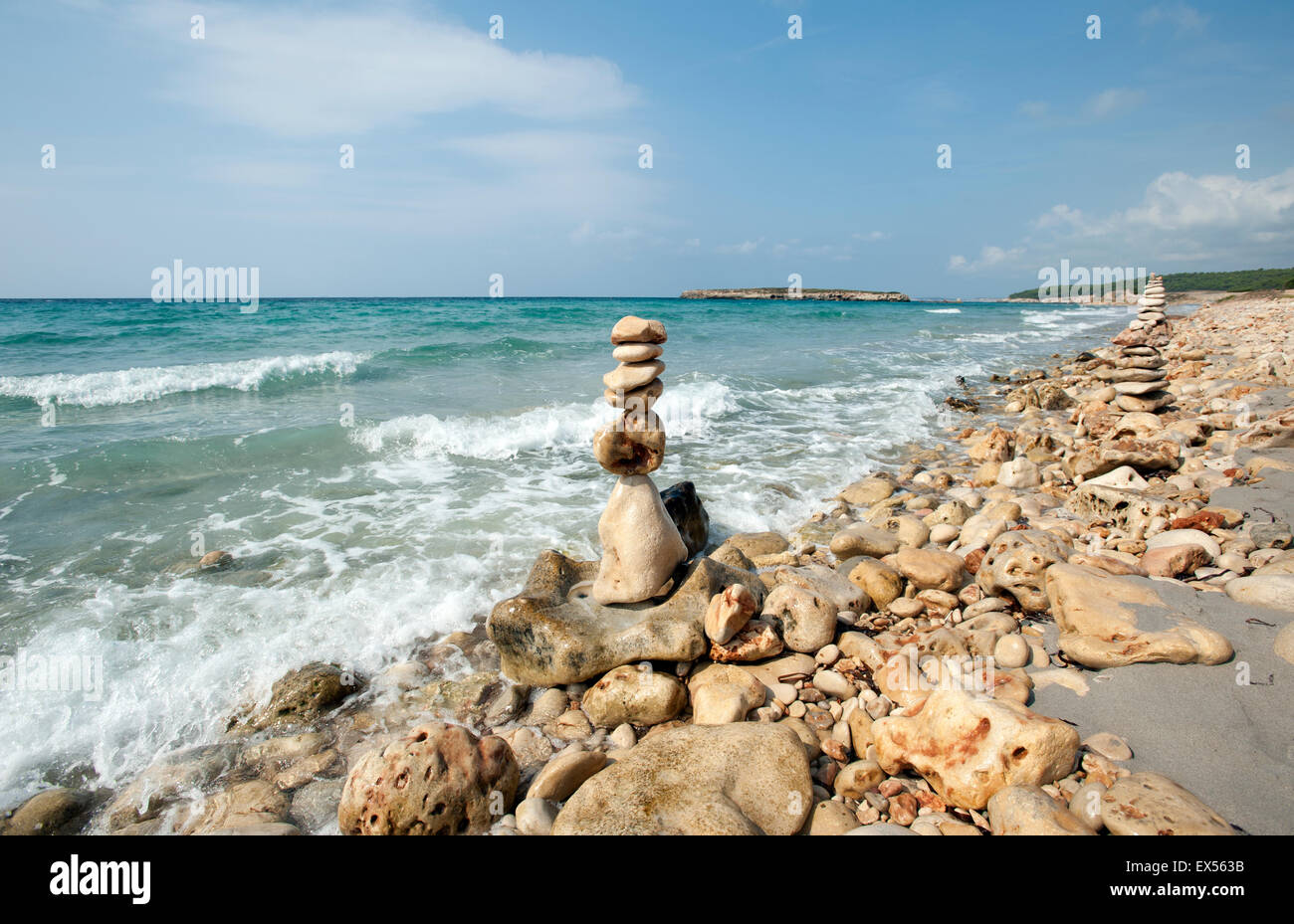 A pile of beach stones made into sculpture towers on the shoreline of Sant Tomas beach on the island of Menorca Spain Stock Photo