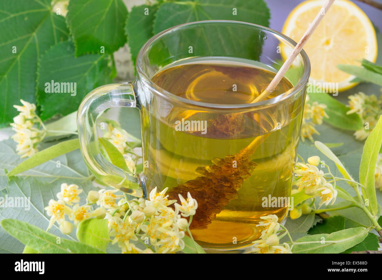 Cup of natural lime tea with sugar stick, lemon and lime flowers Stock Photo