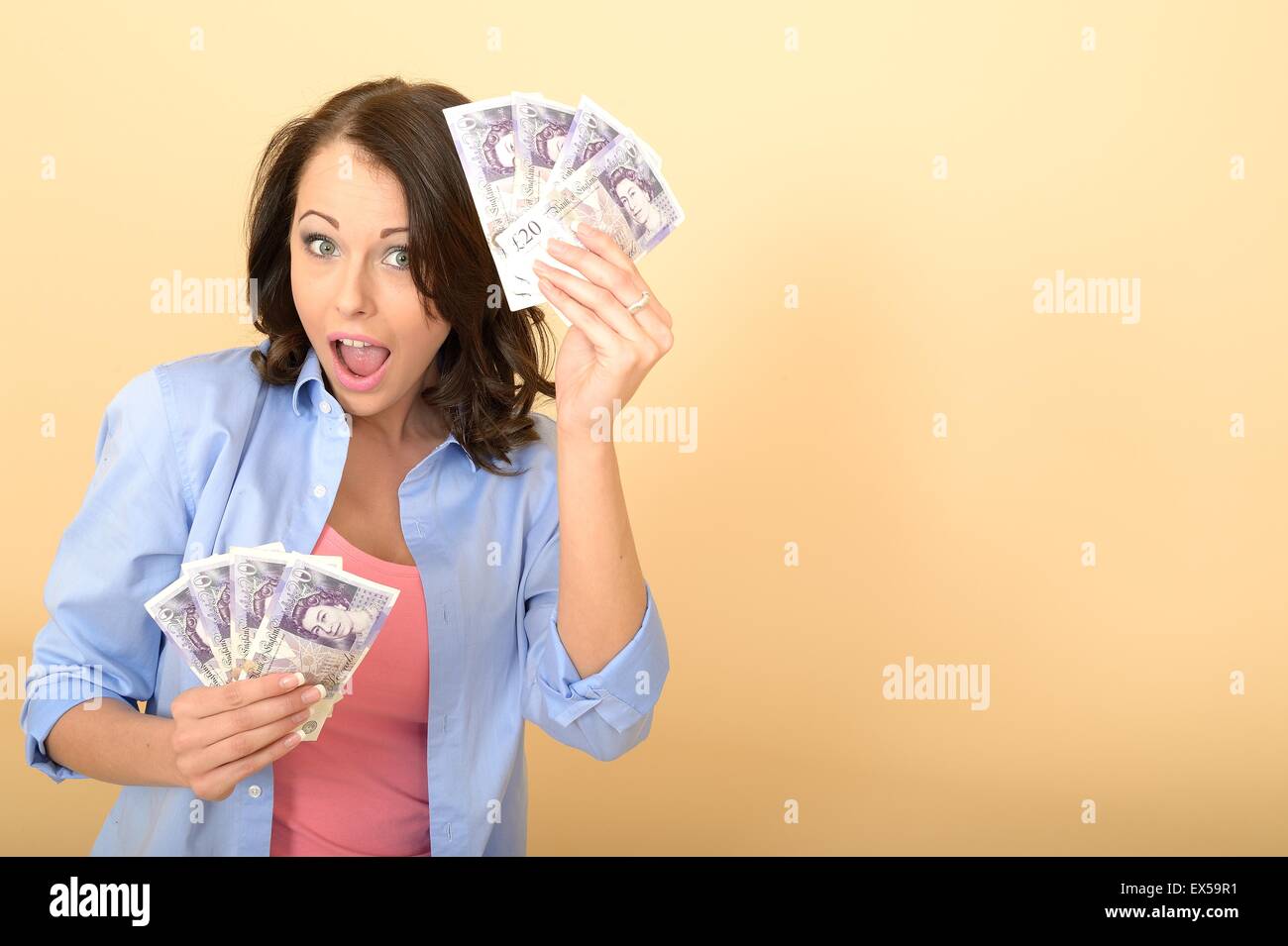 Attractive Young Happy Woman Holding A Handful Of British Twenty Pound Notes Money Or Cash Looking Pleased and Delighted Sitting on The Floor Alone Stock Photo