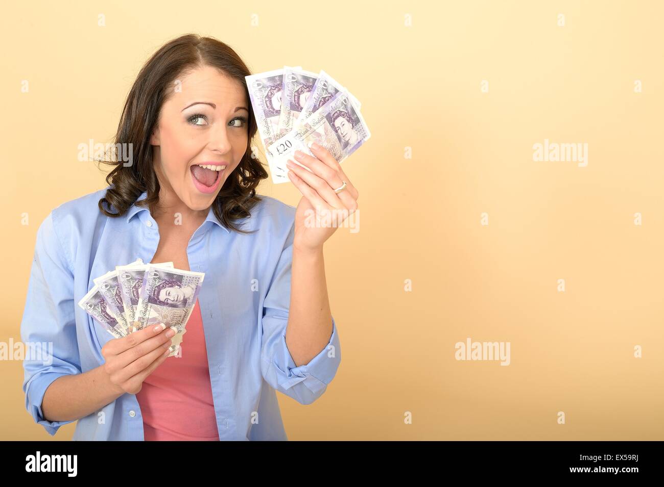 Attractive Young Happy Woman Holding A Handful Of British Twenty Pound Notes Money Or Cash Looking Pleased and Delighted Sitting on The Floor Alone Stock Photo
