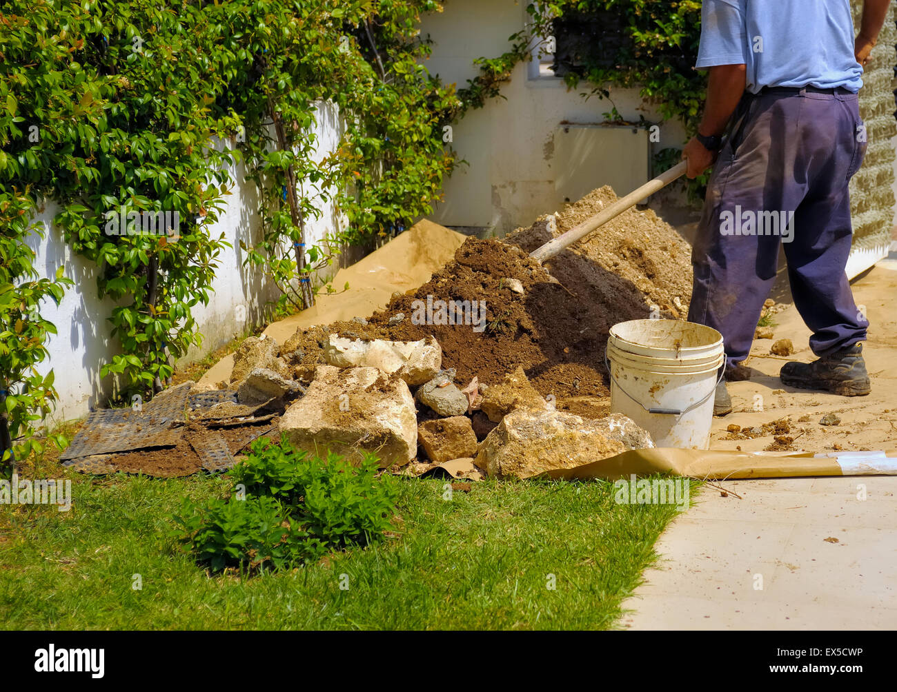 Gardener digging over soil in an garden with a stainless steel garden spade, with a mound of soil on the blade of the spade. Stock Photo
