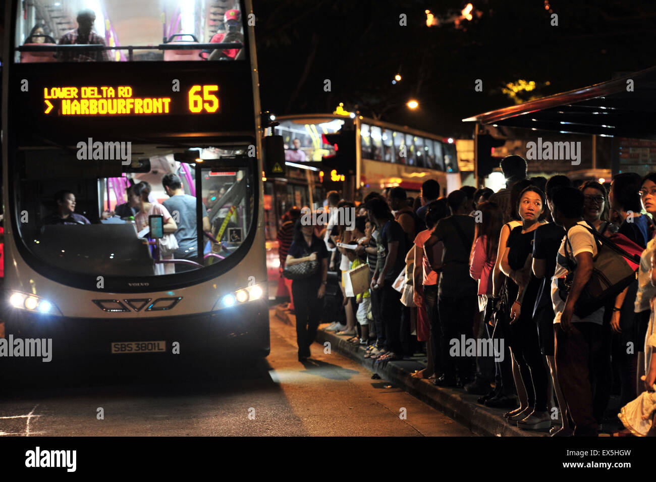 Singapore. 7th July, 2015. People gather to wait for alternative public transport outside a bus stop near Singapore's Dhoby Ghaut MRT Station on July 7, 2015. Train services on Singapore's North-South and East-West MRT Lines were disrupted at evening peak hours due to electrical malfunction on Tuesday, the second time after the East-West MRT Line malfunction in March. © Then Chih Wey/Xinhua/Alamy Live News Stock Photo