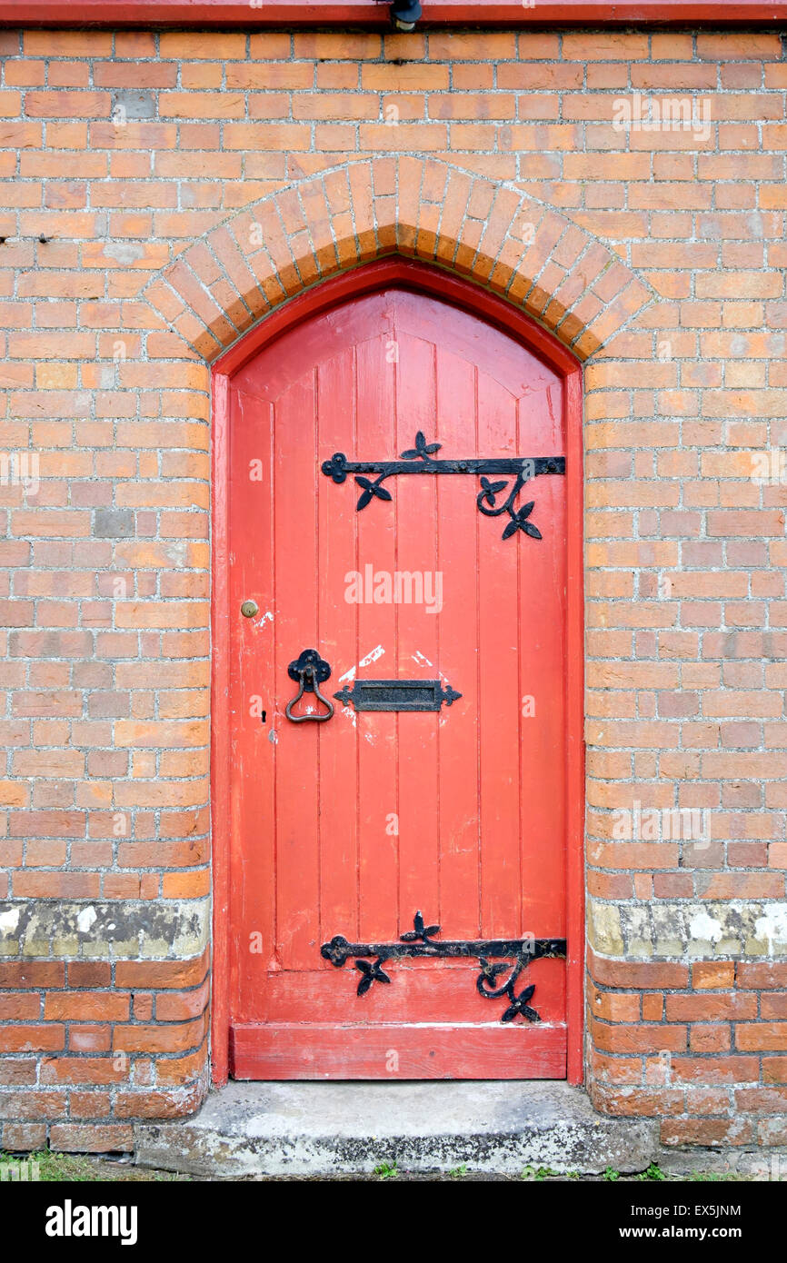 Old red painted wooden door with ornate wrought iron furniture Stock Photo