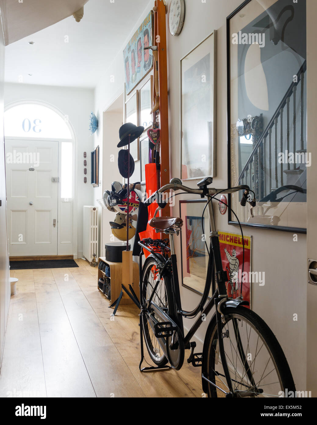 Vintage style bicycle in funky entrance hall with various artwork and hat and shoe racks designed by Sebastian Conran Stock Photo