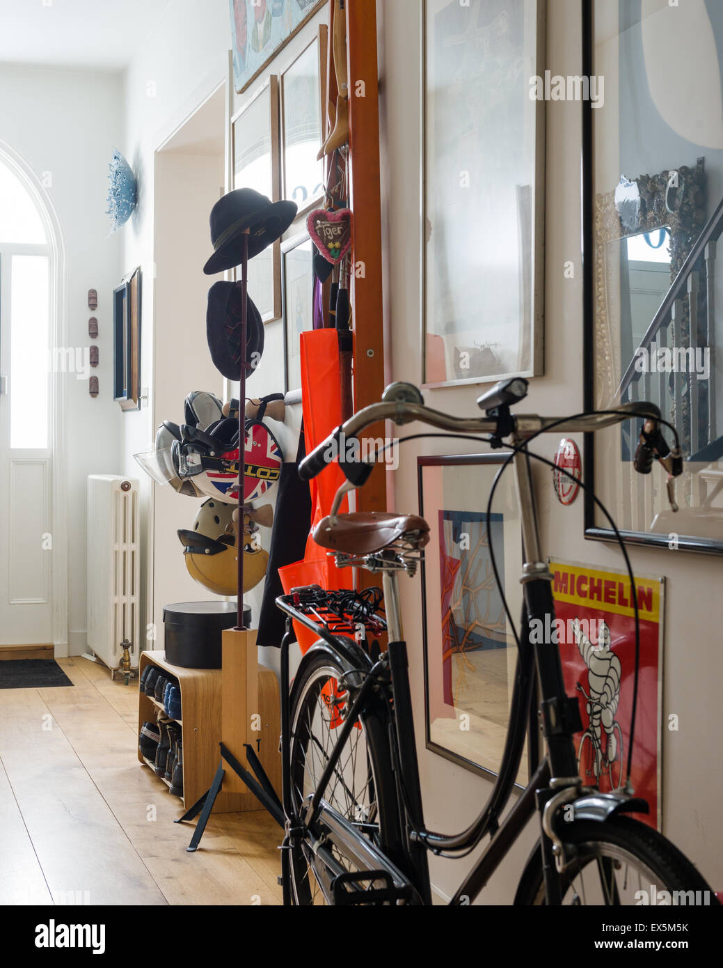 Vintage style bicycle in funky entrance hall with various artwork and hat and shoe racks designed by Sebastian Conran Stock Photo