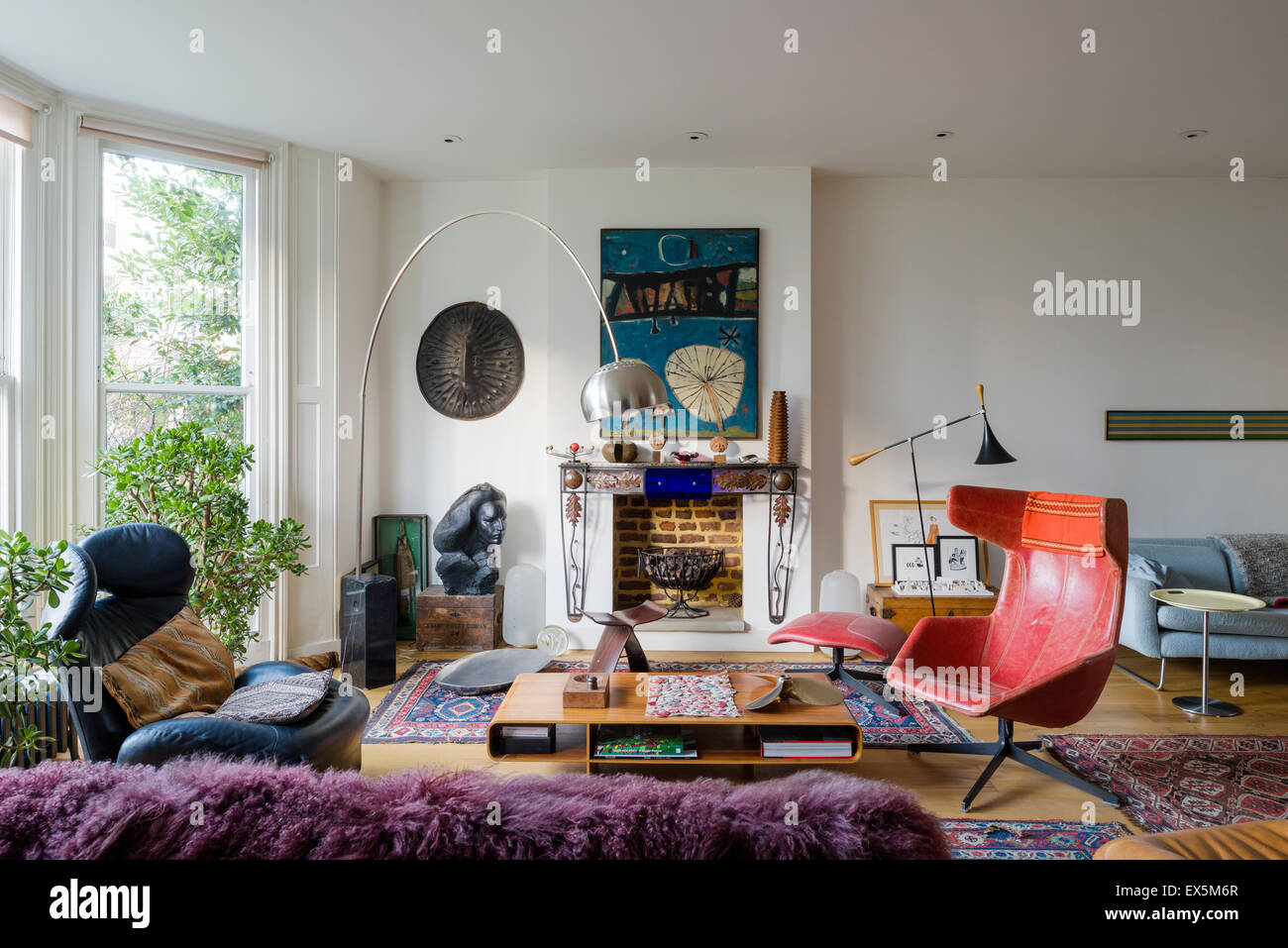 Bright drawing room filled with eclectic furniture. The Arc lamp is by Archille Castiglione, the coffee table by Barber Oserby Stock Photo