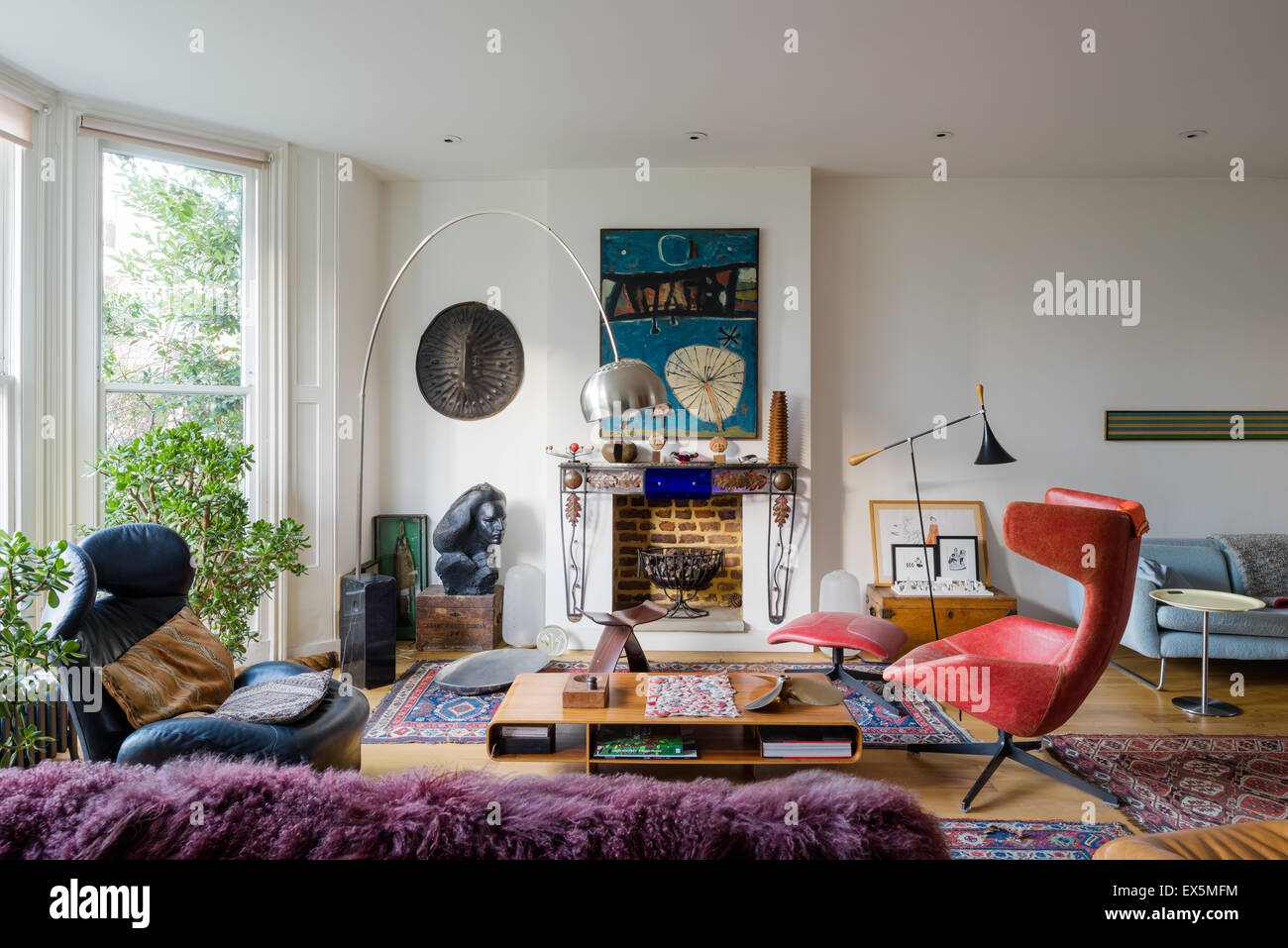 Bright drawing room filled with eclectic furniture. The Arc lamp is by Archille Castiglione, the coffee table by Barber Oserby Stock Photo