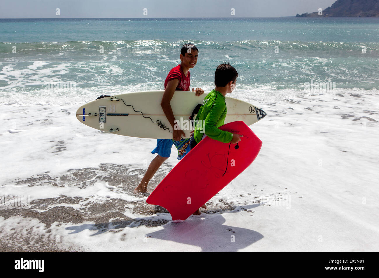 Two boys with surf boards, go on the beach, Plakias, Crete, Greek Island, Greece Stock Photo