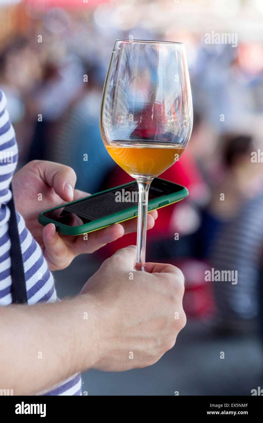 man holding a glass of wine and writes SMS on phone Stock Photo