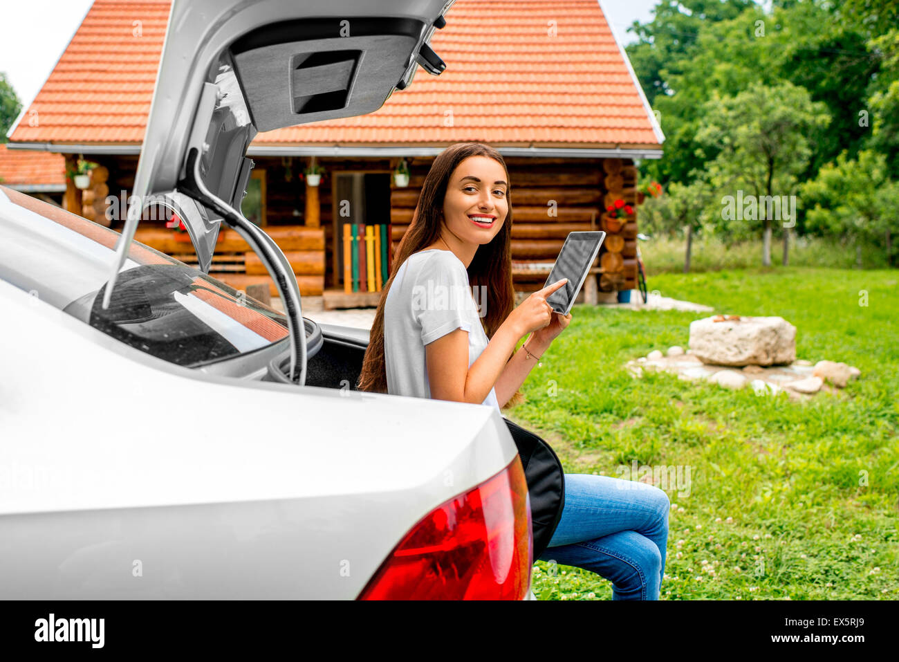 Woman packing near the car with house on backgraound Stock Photo