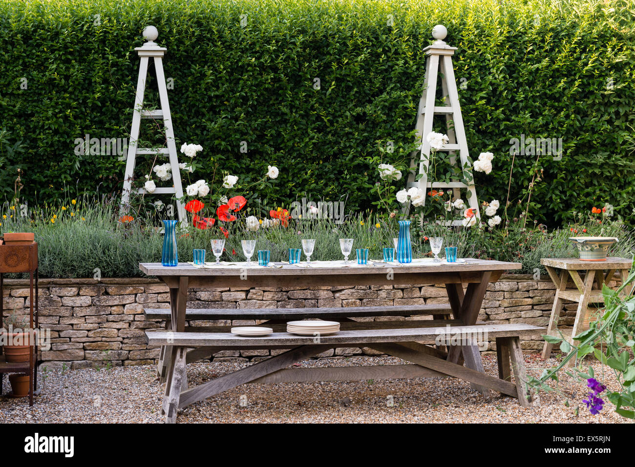 Picnic bench in garden with lavender bed and plant stands Stock Photo