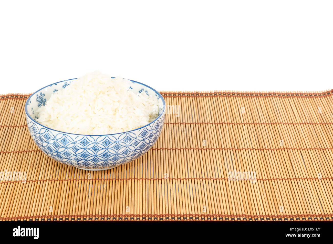 Bowl of rice on placemat in Asian style against white background Stock Photo