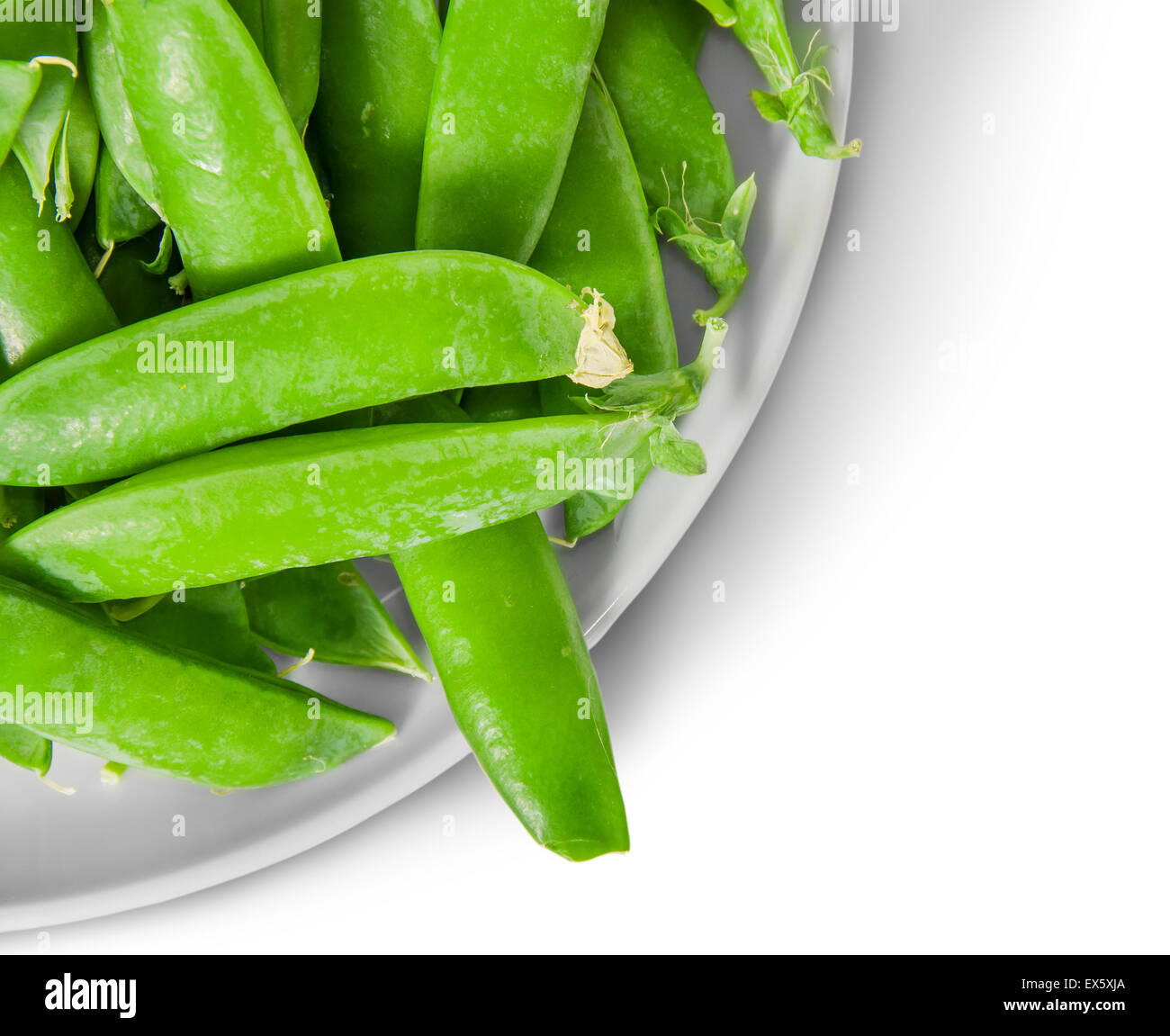 Closeup green peas in pods on white plate top view isolated on white background Stock Photo