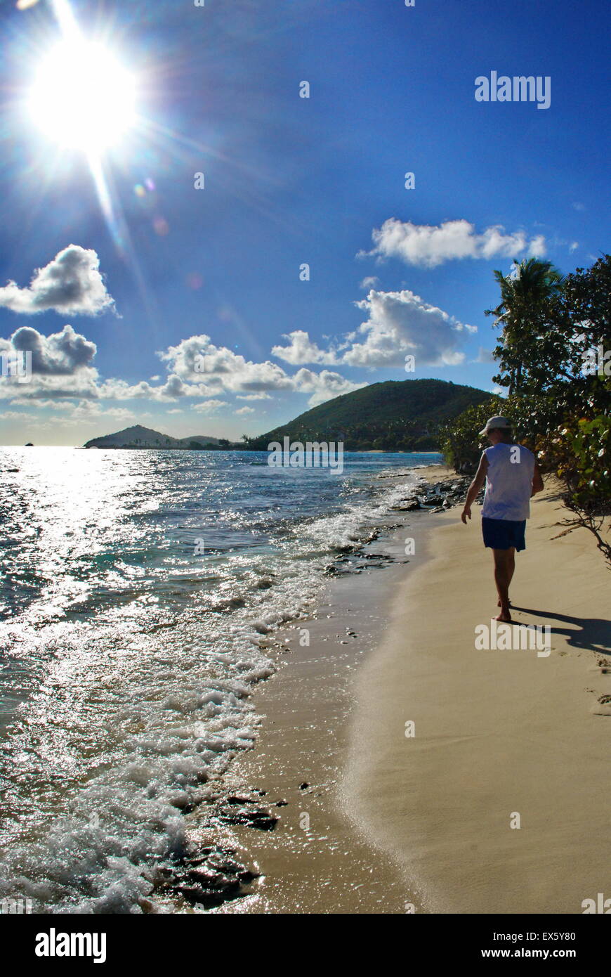 Man walking on Caribbean beach with sun in photo Stock Photo - Alamy