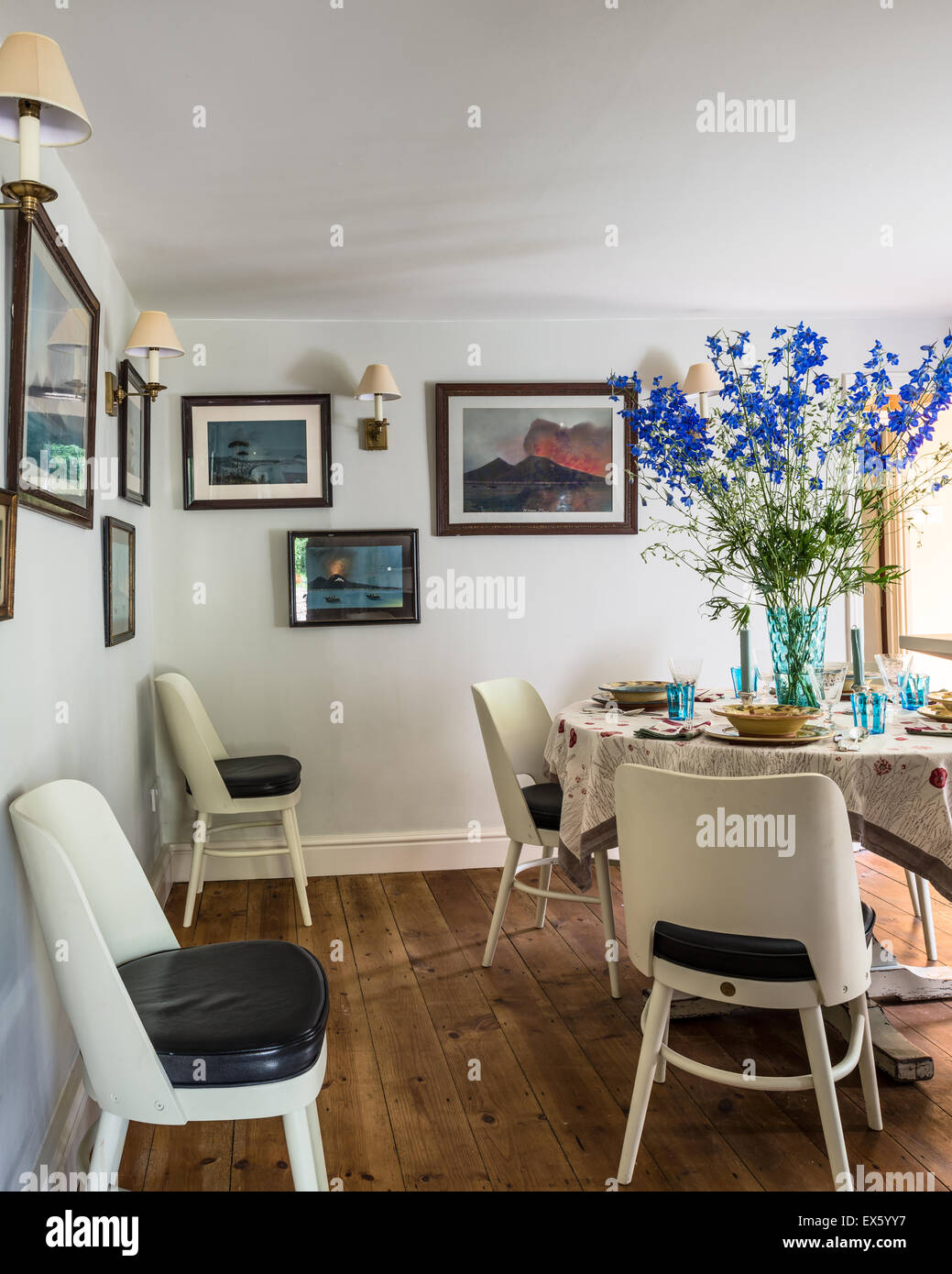 Painted chairs with leather seats by Christopher Howe in dining room with  artworks of Vesuvius Stock Photo