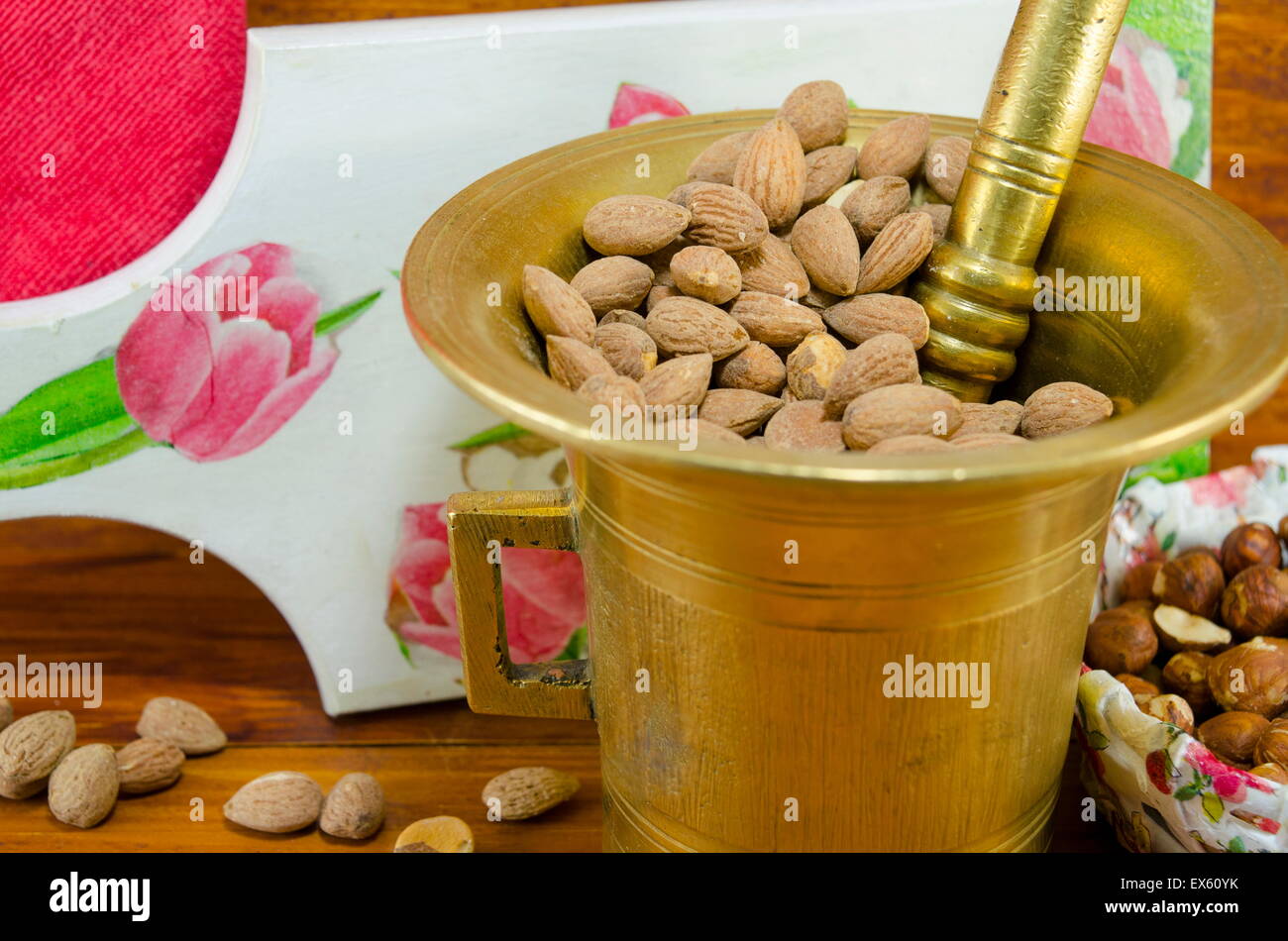 Hazelnuts in a old mortar with an decoupage decorated tray in background on a table with nuts and almonds in a bowl Stock Photo