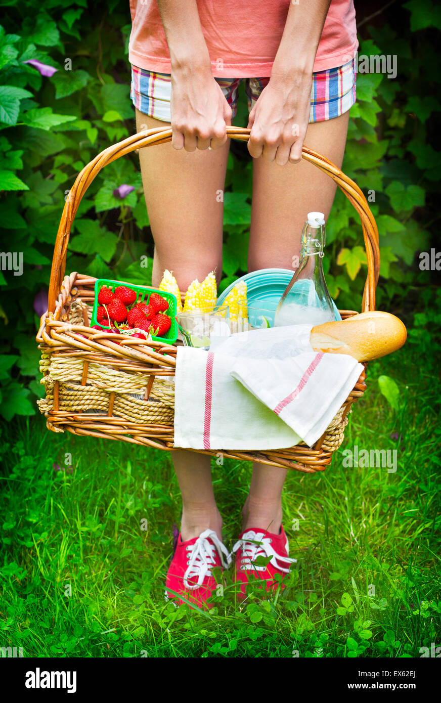 Young girl holding a picnic basket with berries, lemonade and bread. Stock Photo