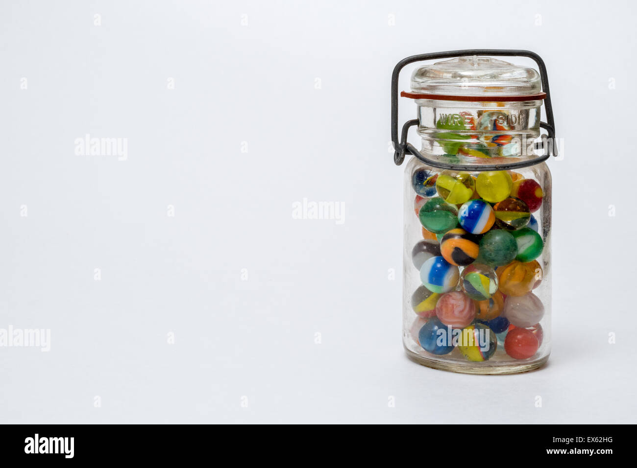 Glass Jar full of Colorful Glass Marbles with Closed Lid Metal Wire Stock Photo