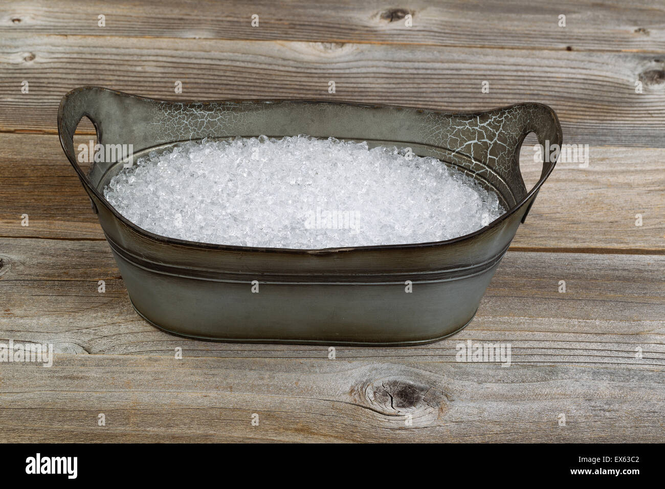 Vintage metal tub shaped bucket filled with crushed ice on rustic