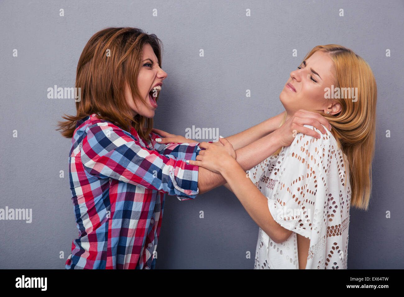 Two girl friends quarrel over gray background Stock Photo