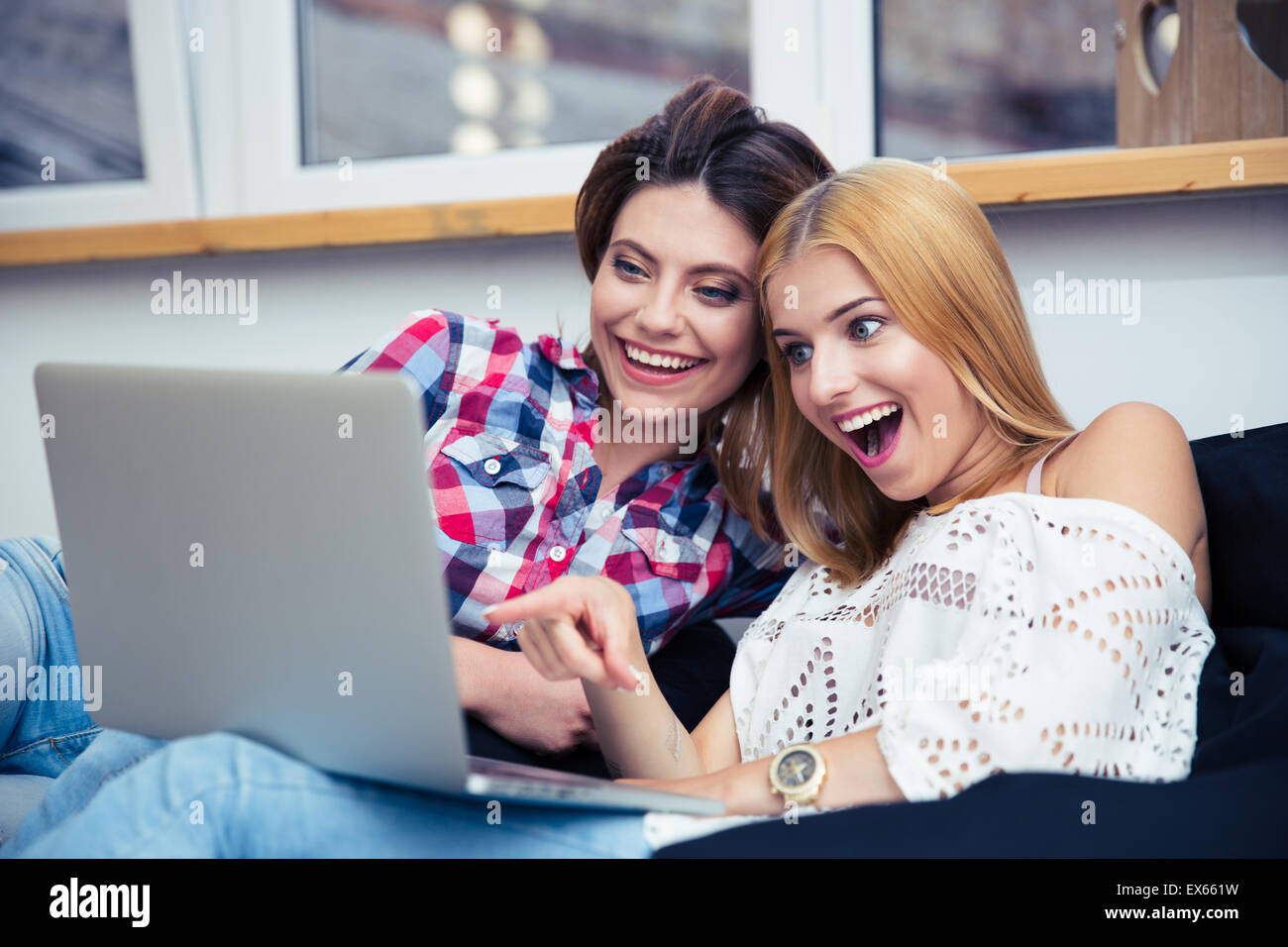 Two cheerful women sitting on sofa and watching movie on laptop Stock ...