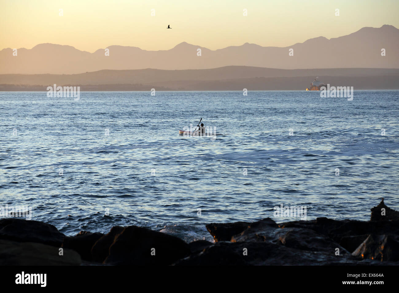 Man paddles kayak along the Mossel Bay coastline Stock Photo