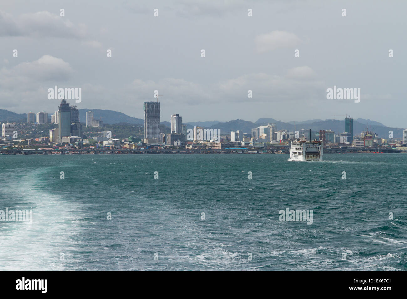 Skyline View of Cebu City from Lite Ferry with Wake Trailing in Water Behind Boat on Island of Cebu, Philippines Stock Photo