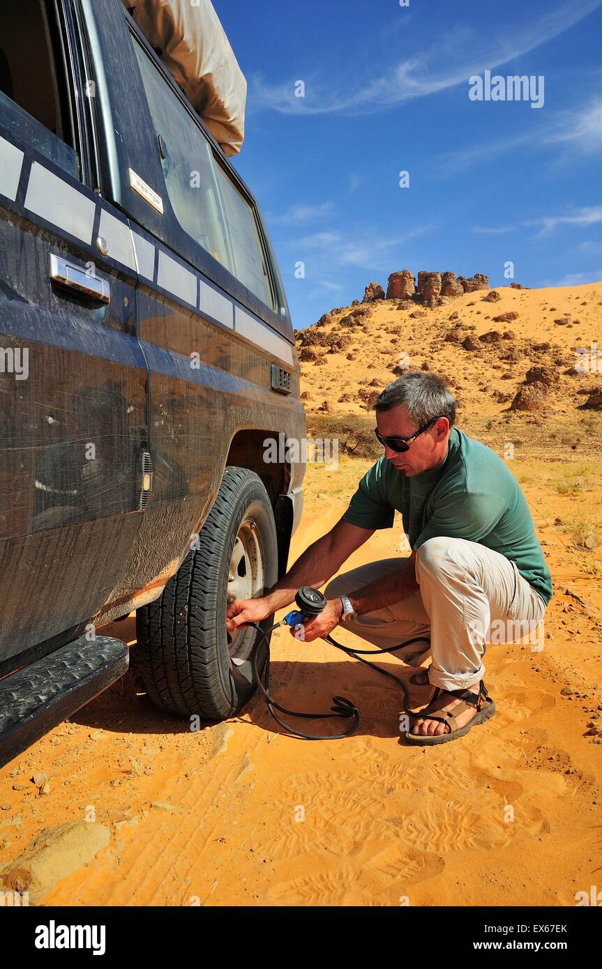 Man letting air out of the tires before driving on a road with soft sand, route from Atar to Tidjikja, Adrar region, Mauritania Stock Photo
