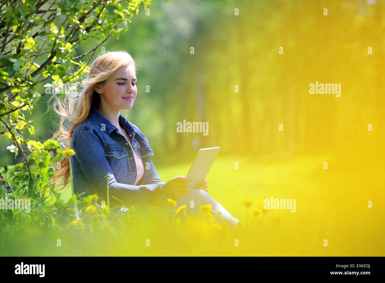 Young woman using tablet in spring park with flowers Stock Photo