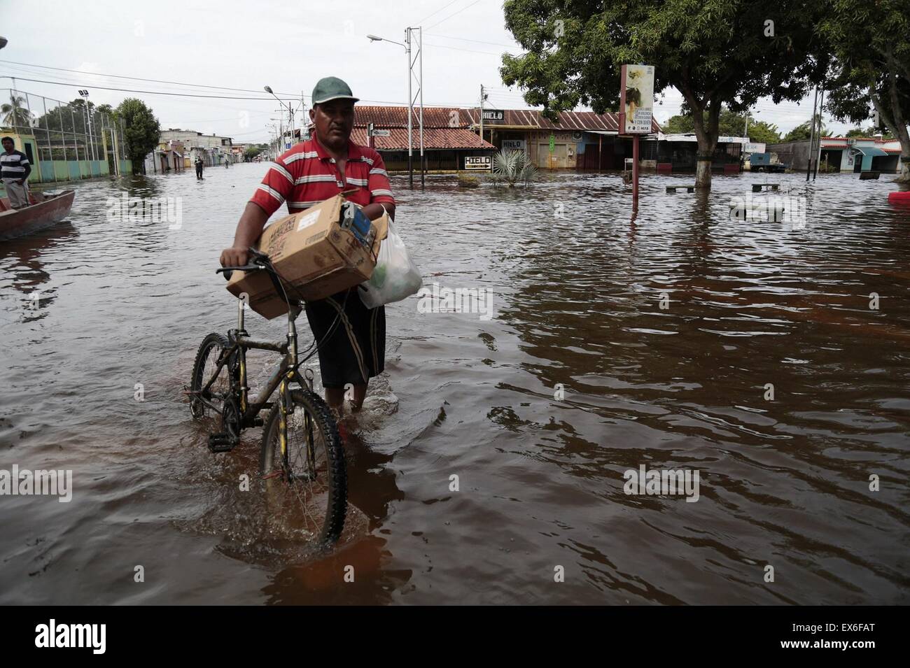 Apure, Venezuela. 7th July, 2015. A person walks with his bicycle in a flooded street in the town of Guasdualito, Apure state, Venezuela, on July 7, 2015. According to local press, more than 9,000 families were affected by the floods caused by the overflowing of the rivers Arauca and Sarare. Credit:  Str/Xinhua/Alamy Live News Stock Photo