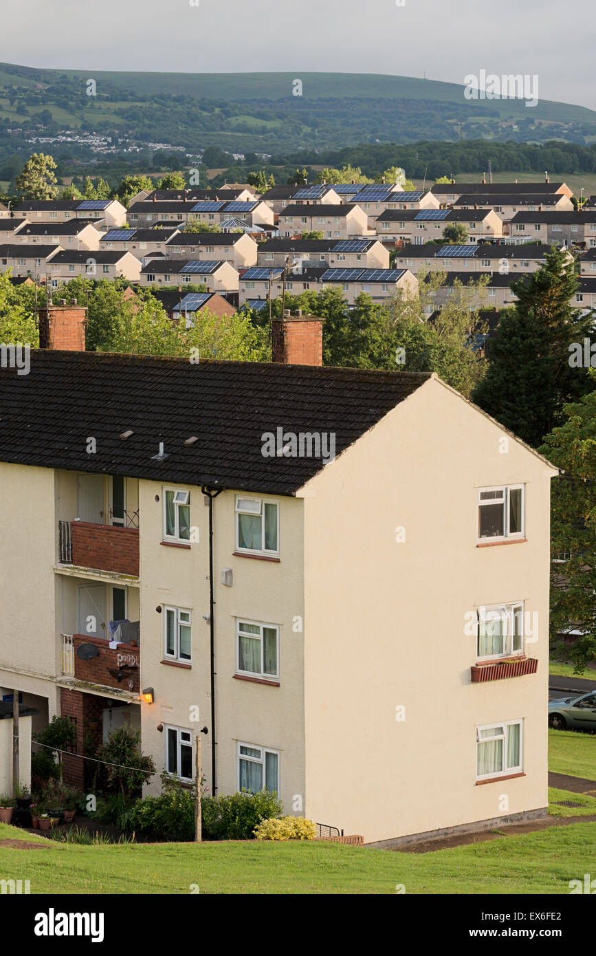 Sunlit housing with solar panelling on the roofs in the Bettws area of Newport City, Wales, Cwmbran can be seen in the distance. Stock Photo