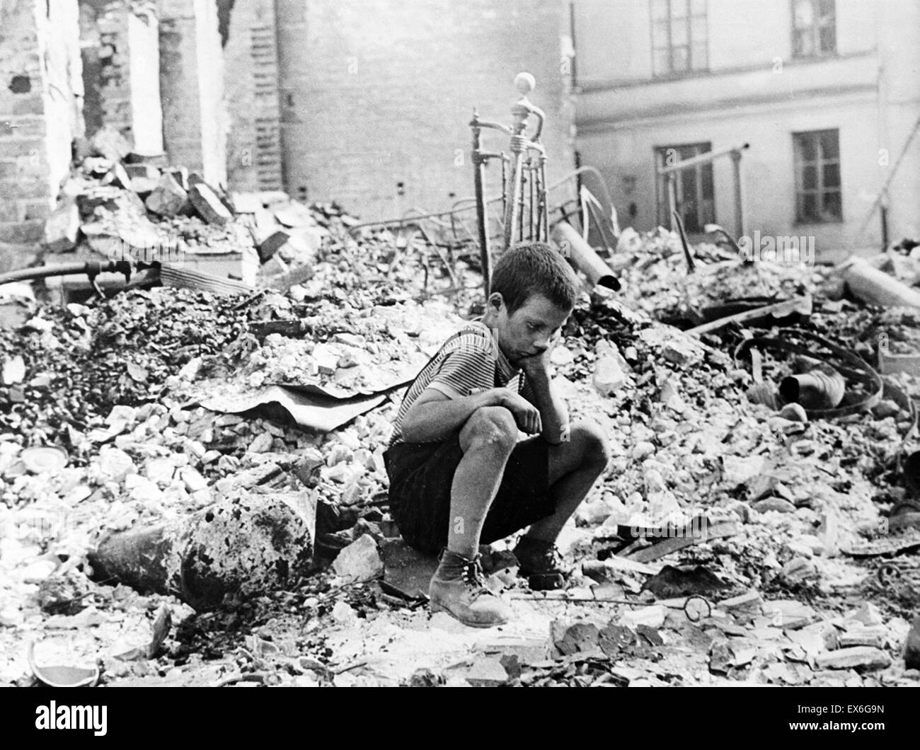 At the beginning of World War two, a Polish boy sits grieving in the ruins of a street in Warsaw, Poland, September 1939 Stock Photo