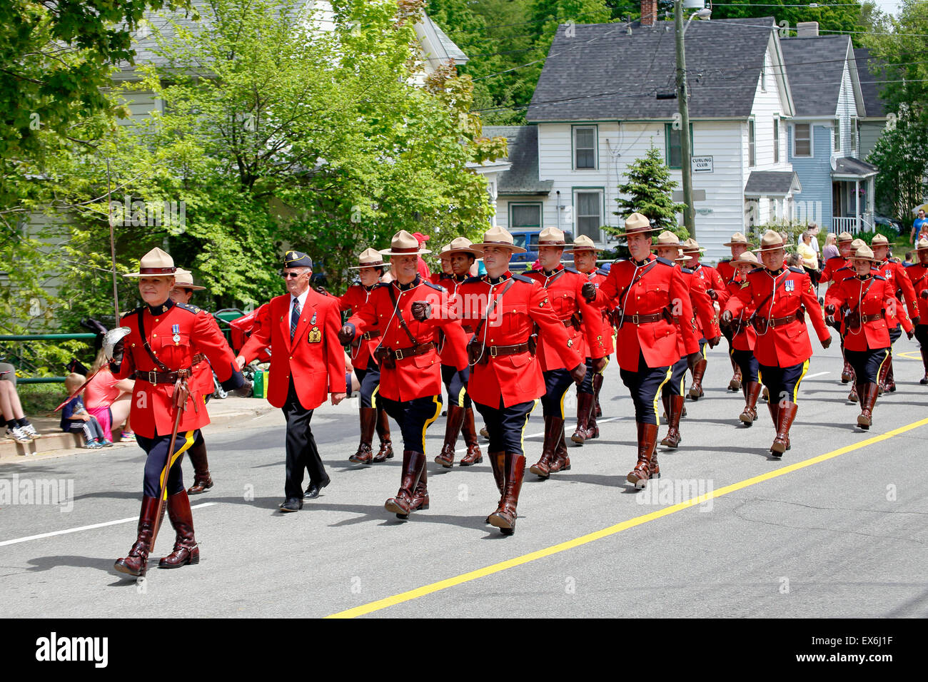 A group of Royal Canadian Mounted Police RCMP officers in red ceremonial uniform marching in a parade lead by a female officer Stock Photo