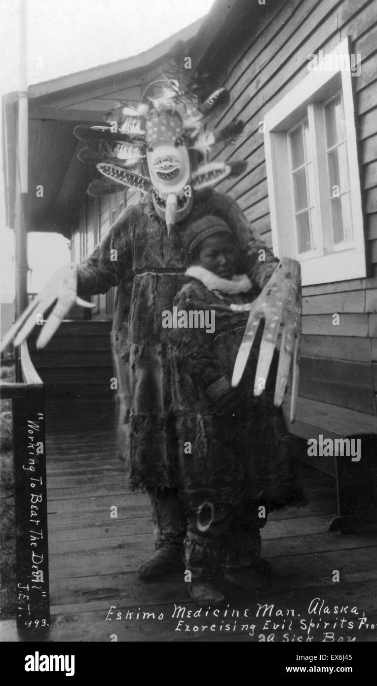 Eskimo medicine man exorcising evil spirits from a sick boy in Alaska USA; [between ca. 1900 and ca. 1930] Stock Photo