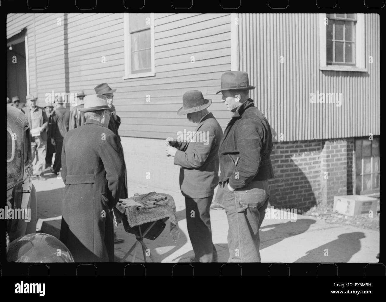 Salesman displaying patent medicine to farmers who have brought tobacco to warehouse and are waiting outside for the sales to begin. Mebane, North Carolina 1939 Stock Photo